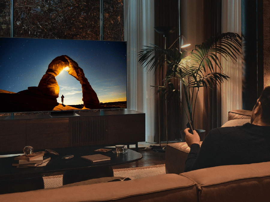 Чоловік перед QLED-телевізором уночі.  На екрані відображається зображення, яке оптимізується для режиму комфорту для очей.  Q80BATXXH
