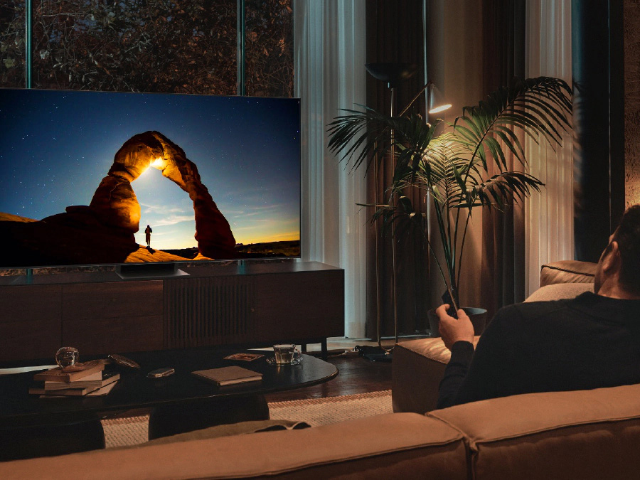 Мужчина перед QLED-телевизором ночью.  На экране отображается изображение, оптимизированное для режима комфорта для глаз.