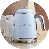 На стільниці стоїть світло-блакитний чайник Smeg з хромованою ручкою.