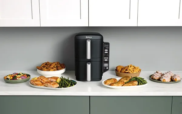 Аерофритюрниця Ninja із закритими шухлядами, оточена тарілками зі стравами: курка, овочі, картопля фрі та випічка