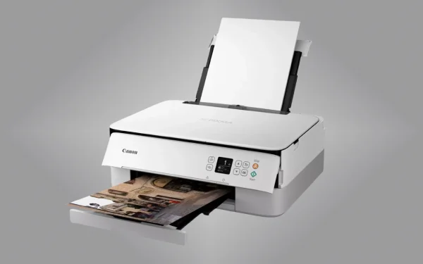 Принтер Canon PIXMA друкує фотографію, зйомка під кутом, з лотком для паперу видно ззаду, сірий фон