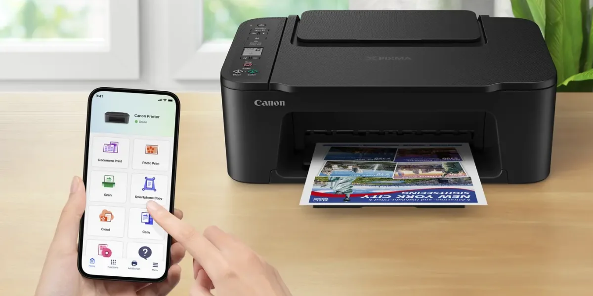Чорний принтер Canon PIXMA TS3750i друкує кольоровий буклет, поруч — смартфон із застосунком.