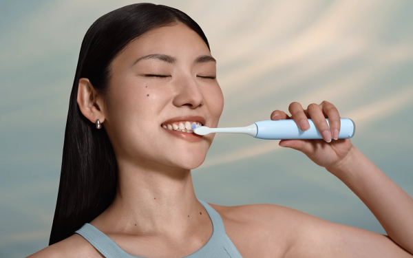 Усміхнена жінка чистить зуби білою зубною щіткою Philips Sonicare HX7406/02.