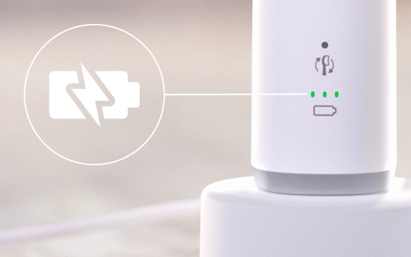 Нижня частина зубної щітки Philips Sonicare HX7400/01 на зарядному пристрої, поруч із нею знаходиться значок батареї та зелені індикатори.