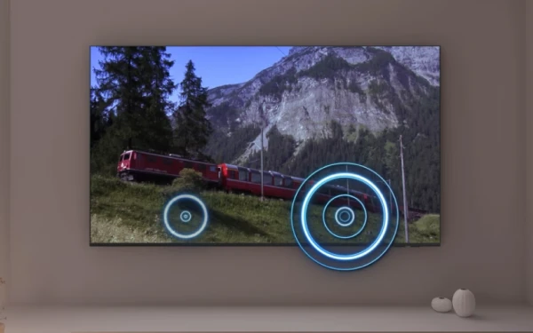 Телевізор на стіні показує поїзд у горах із графікою об'ємного звуку