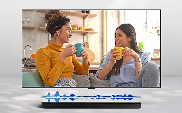 Дві жінки розмовляють на екрані телевізора, а звукова хвиля представляє функцію активного підсилювача голосу (AVA).