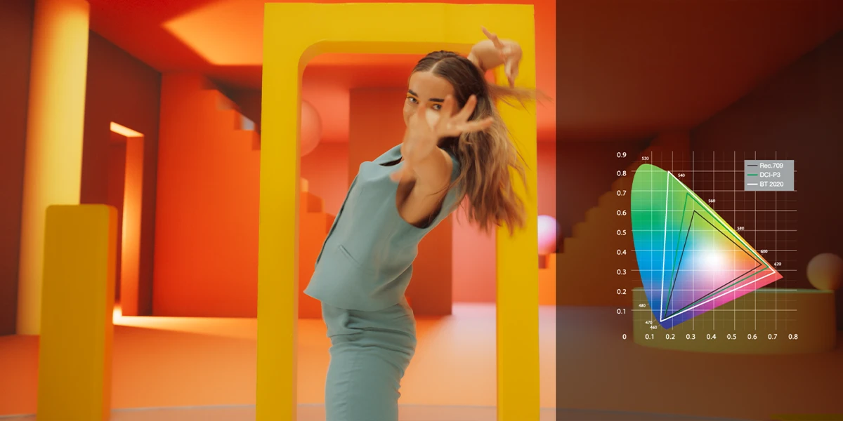 Жінка танцює в барвистому інтер'єрі, збоку видно кольорову гаму лазерного проектора Optoma Photon Go.