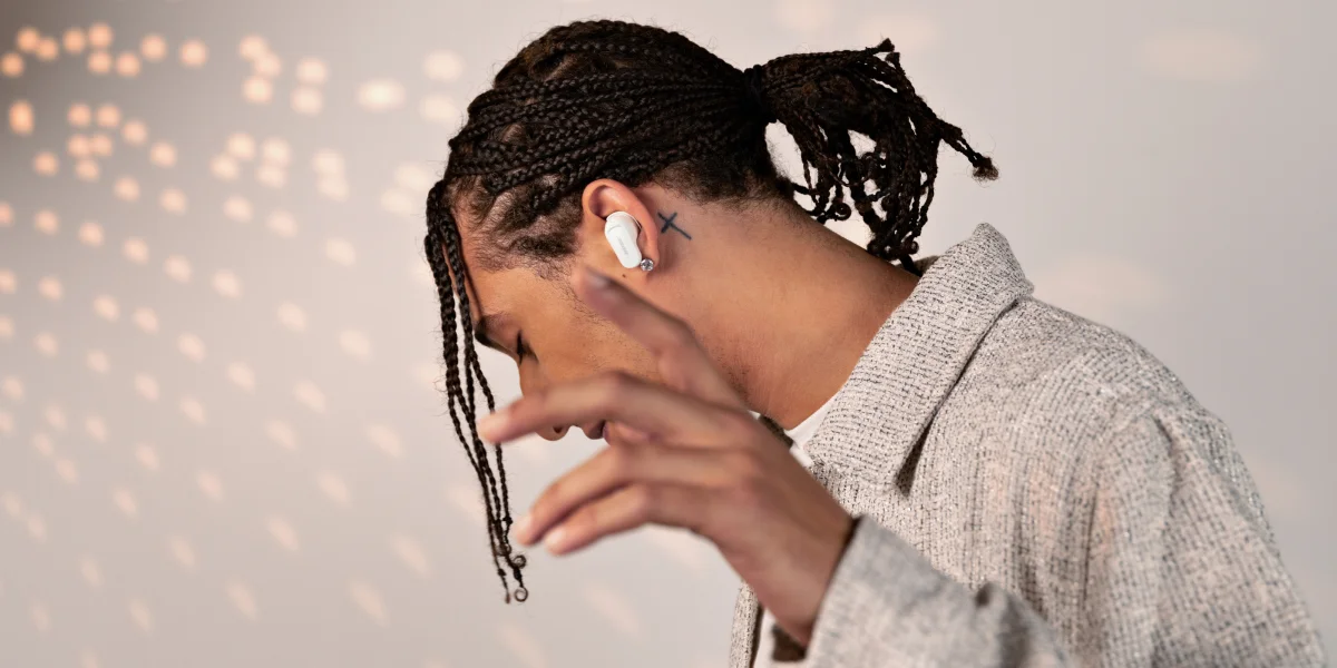 Чоловік у легкій куртці жестикулює, взувши білі навушники Bose.