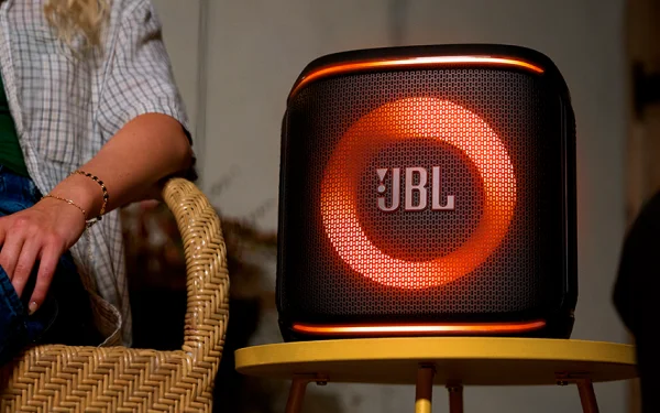 Крупний план колонки JBL з червоним підсвічуванням, що стоїть на невеликому столі.