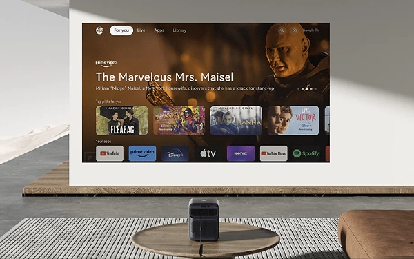 Проектор відображає інтерфейс з фільмами та потоковими додатками на великій білій стіні в сучасній вітальні.