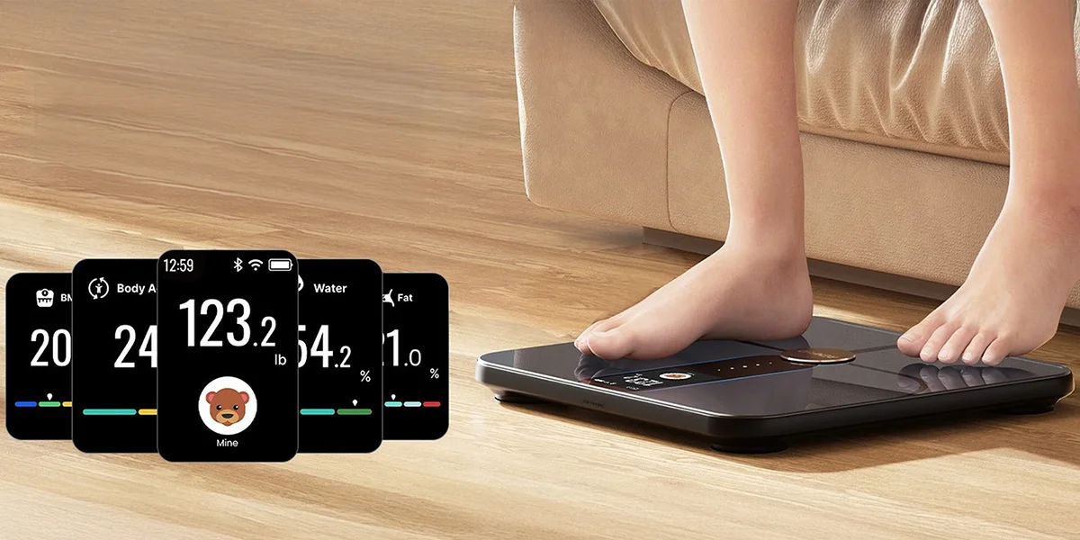 Людина стоїть на вагах Renpho Elis Nova, поруч з якими видно екрани для вимірювання ваги.