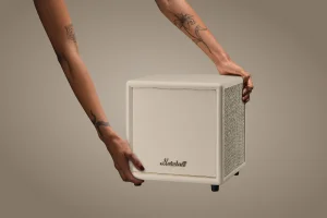 Людина налаштовує кремовий сабвуфер Marshall, вид спереду