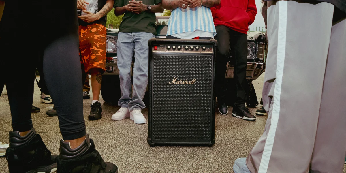 Динамік Marshall стоїть на вулиці в оточенні групи людей та припаркованого автомобіля.