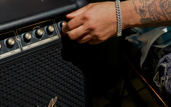 Крупний план руки, яка регулює ручку на динаміку Marshall.