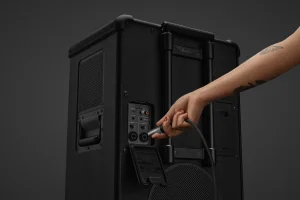 Рука підключає кабель до панелі роз'ємів на задній панелі динаміка