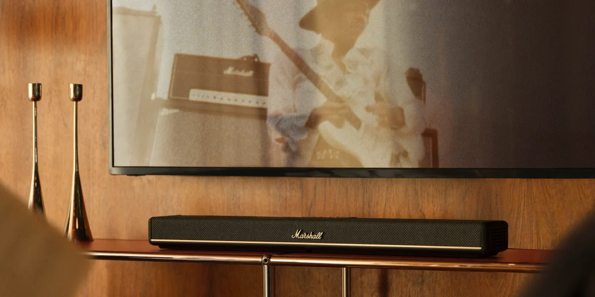 Саундбар Marshall розміщений під телевізором на дерев'яній шафі