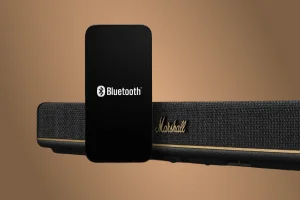 Смартфон із значком Bluetooth перед саундбаром Marshall