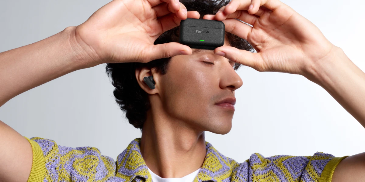 Чоловік з бездротовими навушниками realme у вусі тримає зарядний футляр зі світлодіодом (світлодіодом)